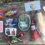 Inhalt eines Geocaches mit Spielkarten, Figuren und Tauschgegenständen auf einem Holzbrett
