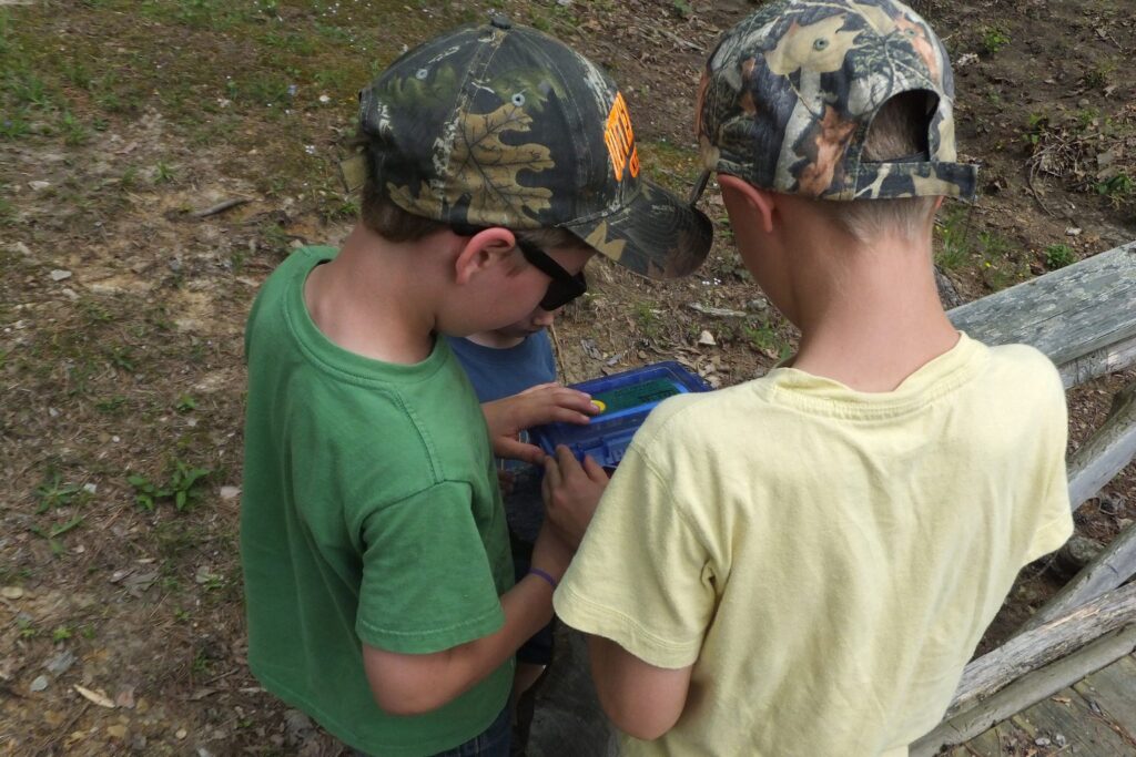 Zwei Kinder mit Kappen schauen gemeinsam auf ein GPS-Gerät